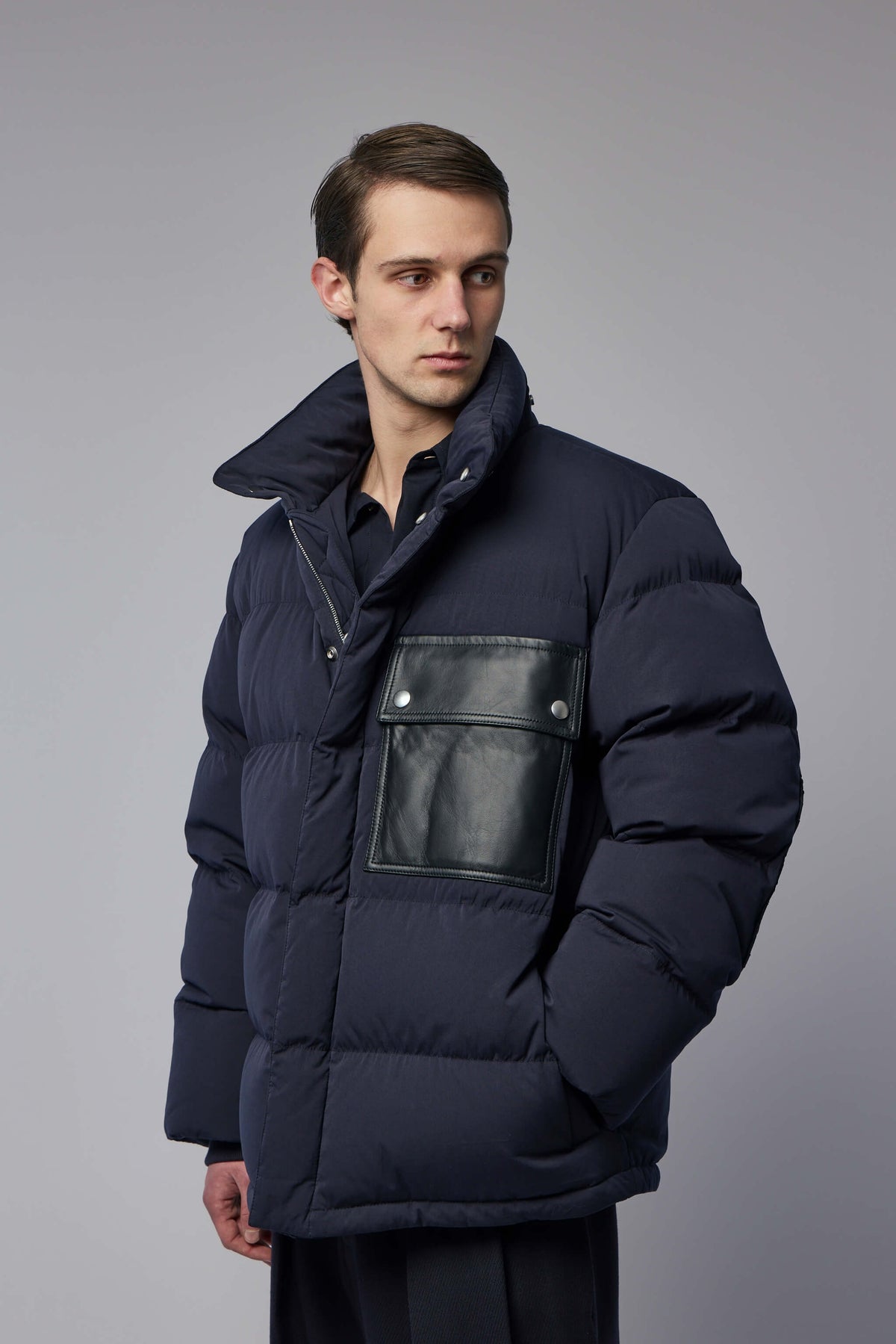 Side profile showing high collar and elbow patch accents on designer down jacket