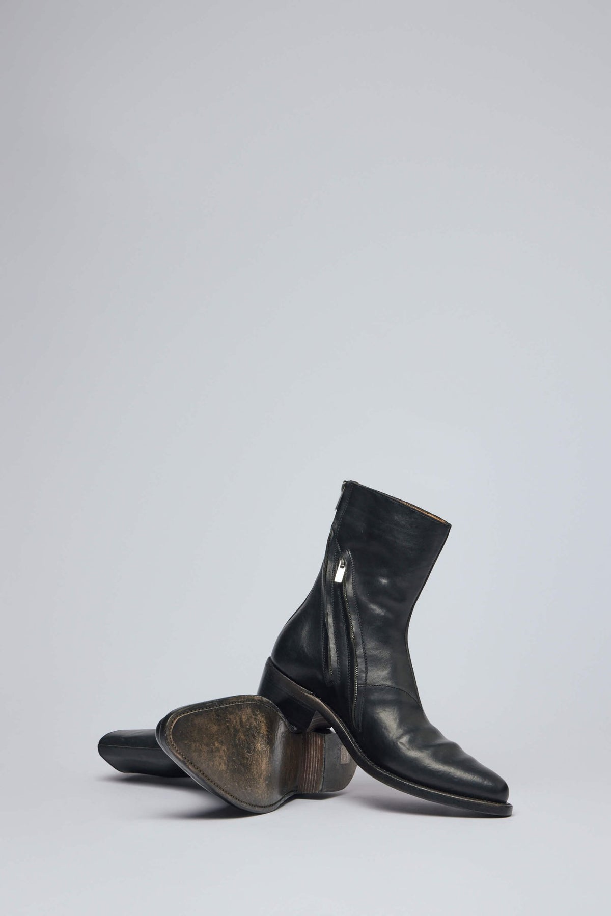 Full view of black leather ankle boots on neutral background