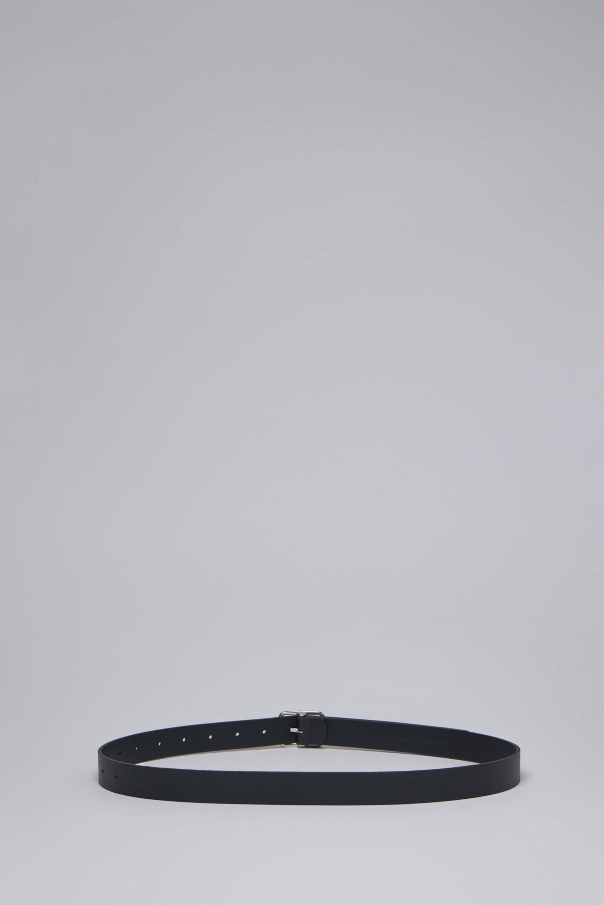 Close-up view of minimalist belt showing smooth leather-like texture and adjustment holes