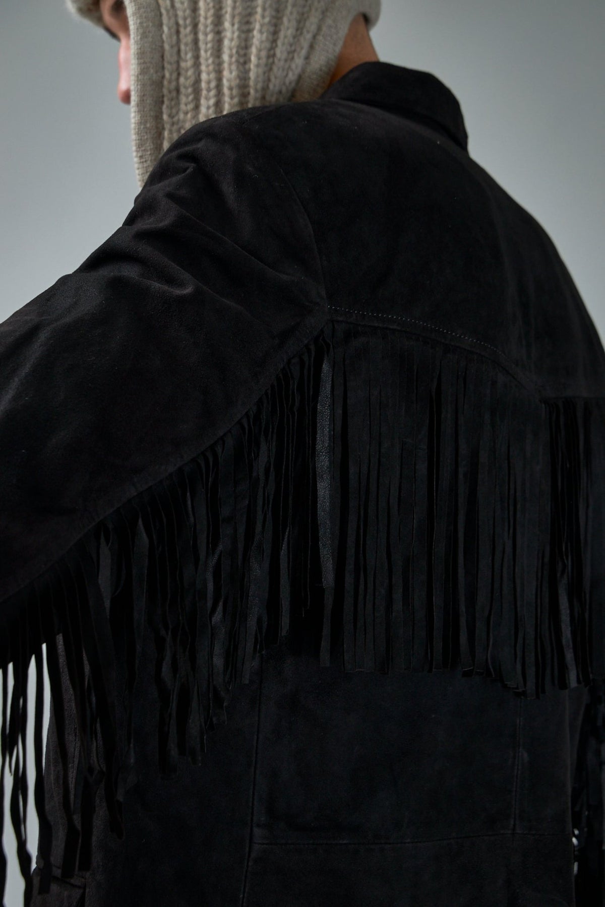 Back view of Adnym leather jacket displaying fringe trim and premium suede finish