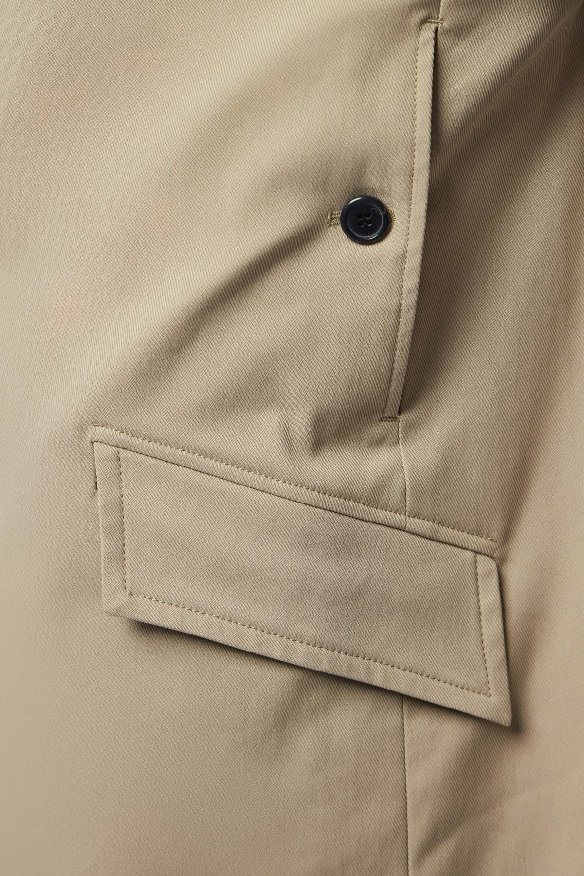 Detail shot of black button closure on neutral tone coat
