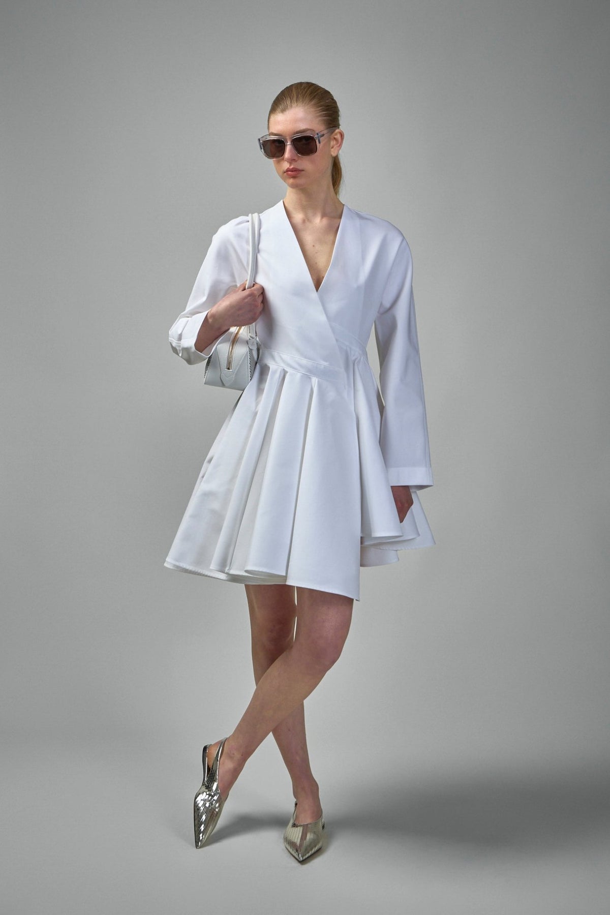 Close-up detail of asymmetric belt feature on Alaïa white poplin mini dress