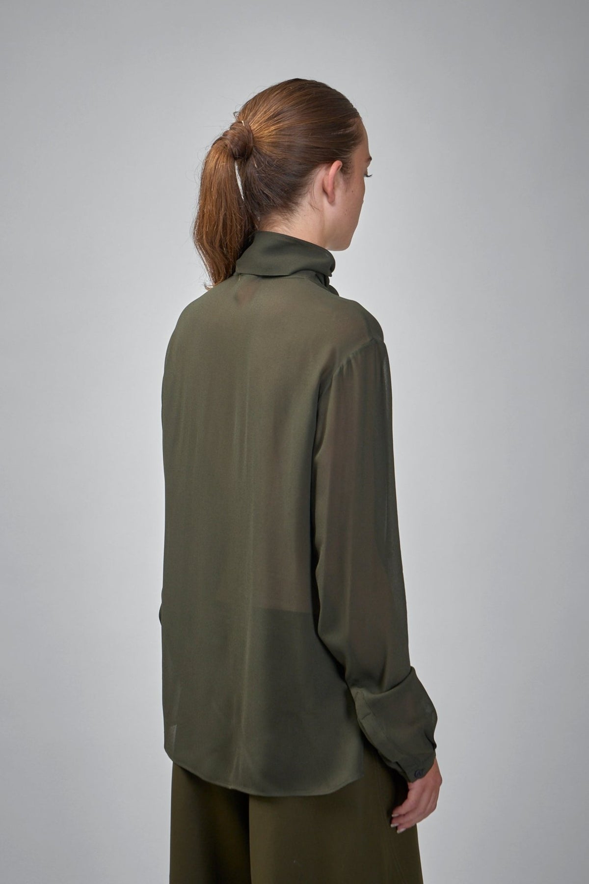 Model wearing Alaïa georgette scarf blouse styled with tailored bottoms