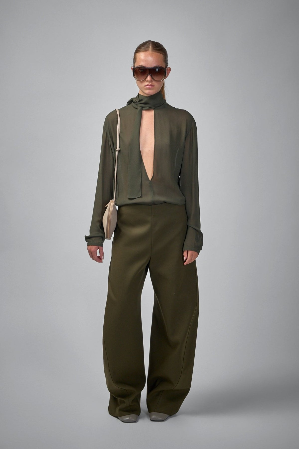 Close-up of Alaïa georgette blouse showing integrated neck tie and sheer fabric texture