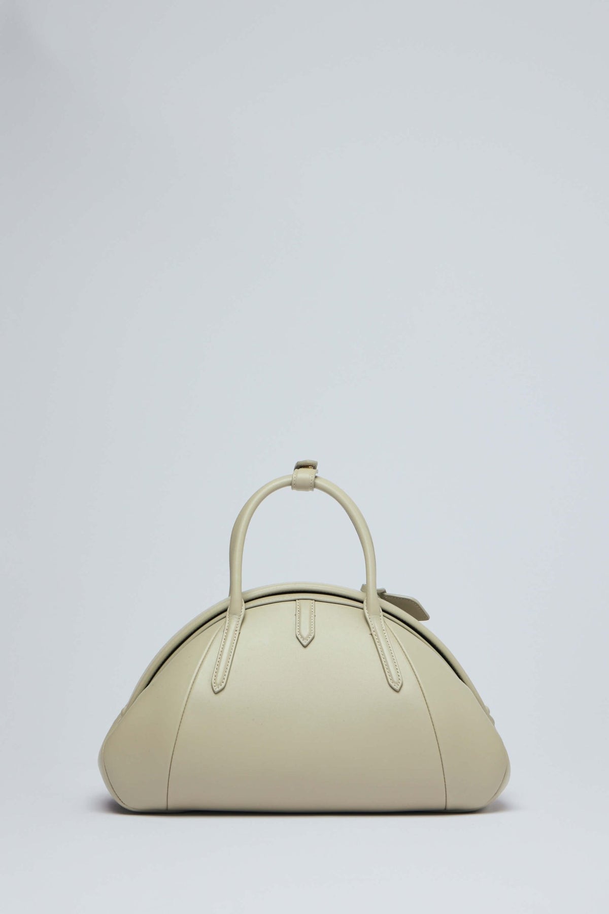 Side profile of Alaïa small top handle bag displaying oval shape design