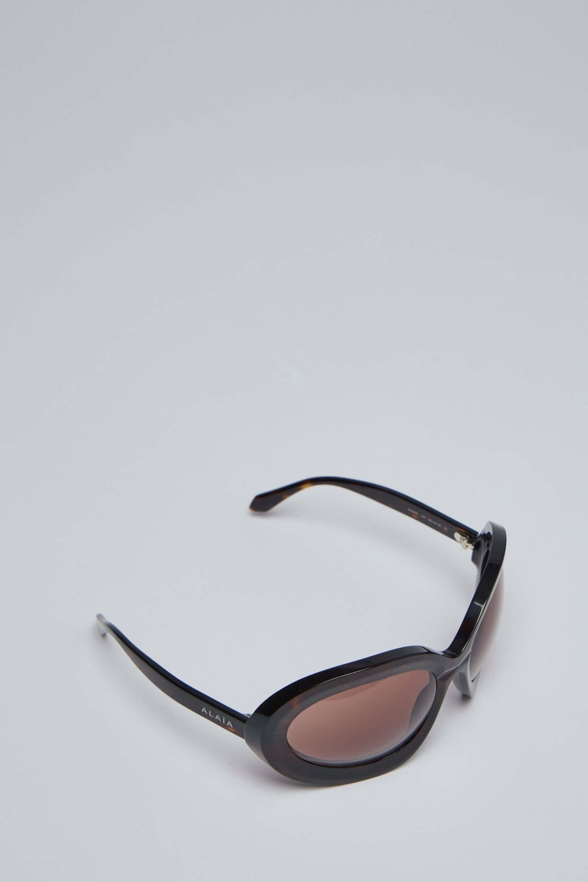 Close-up view of Alaïa Round 101 sunglasses showing curved temple design