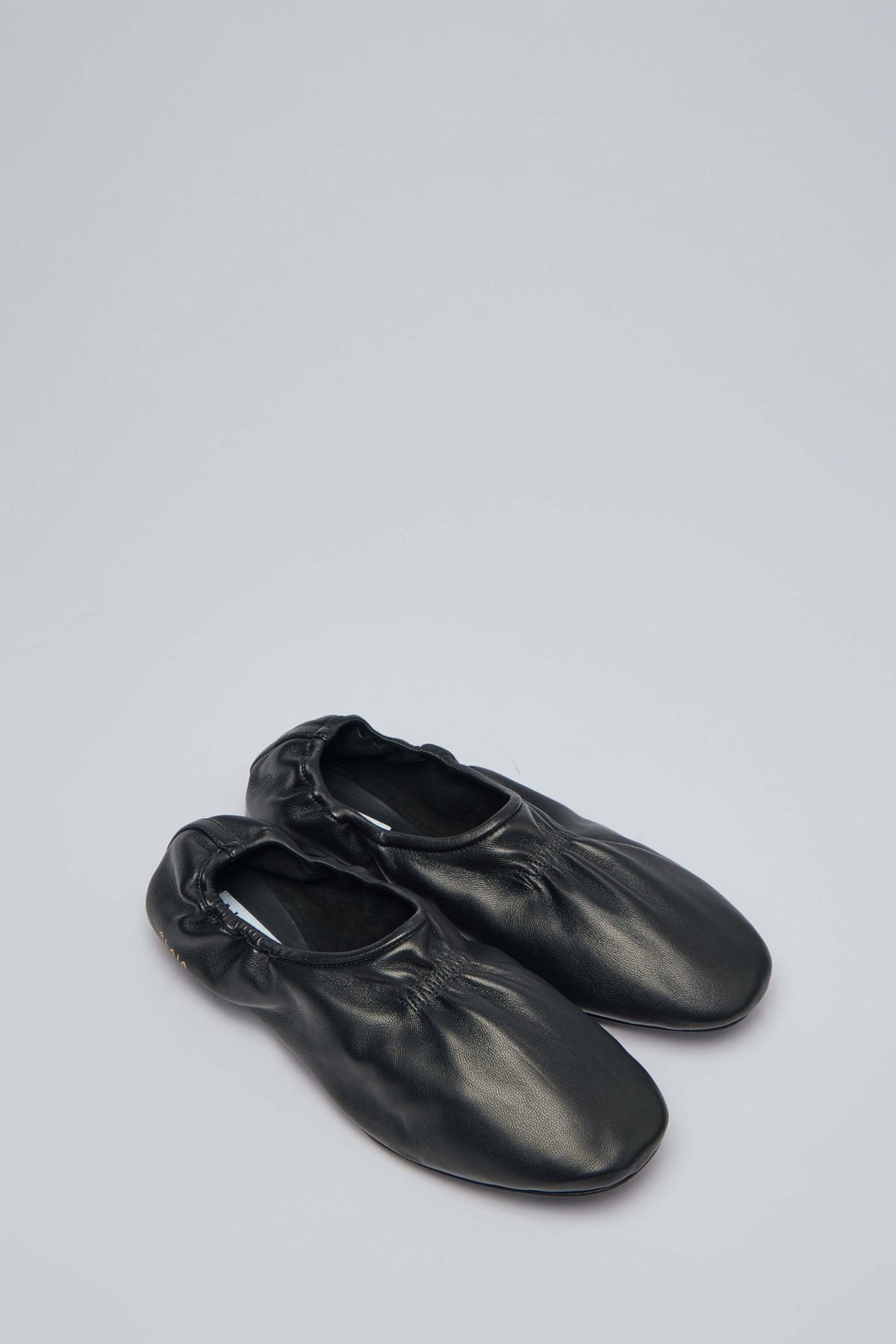 Close-up view of Alaïa leather slippers showing smooth finish and round toe