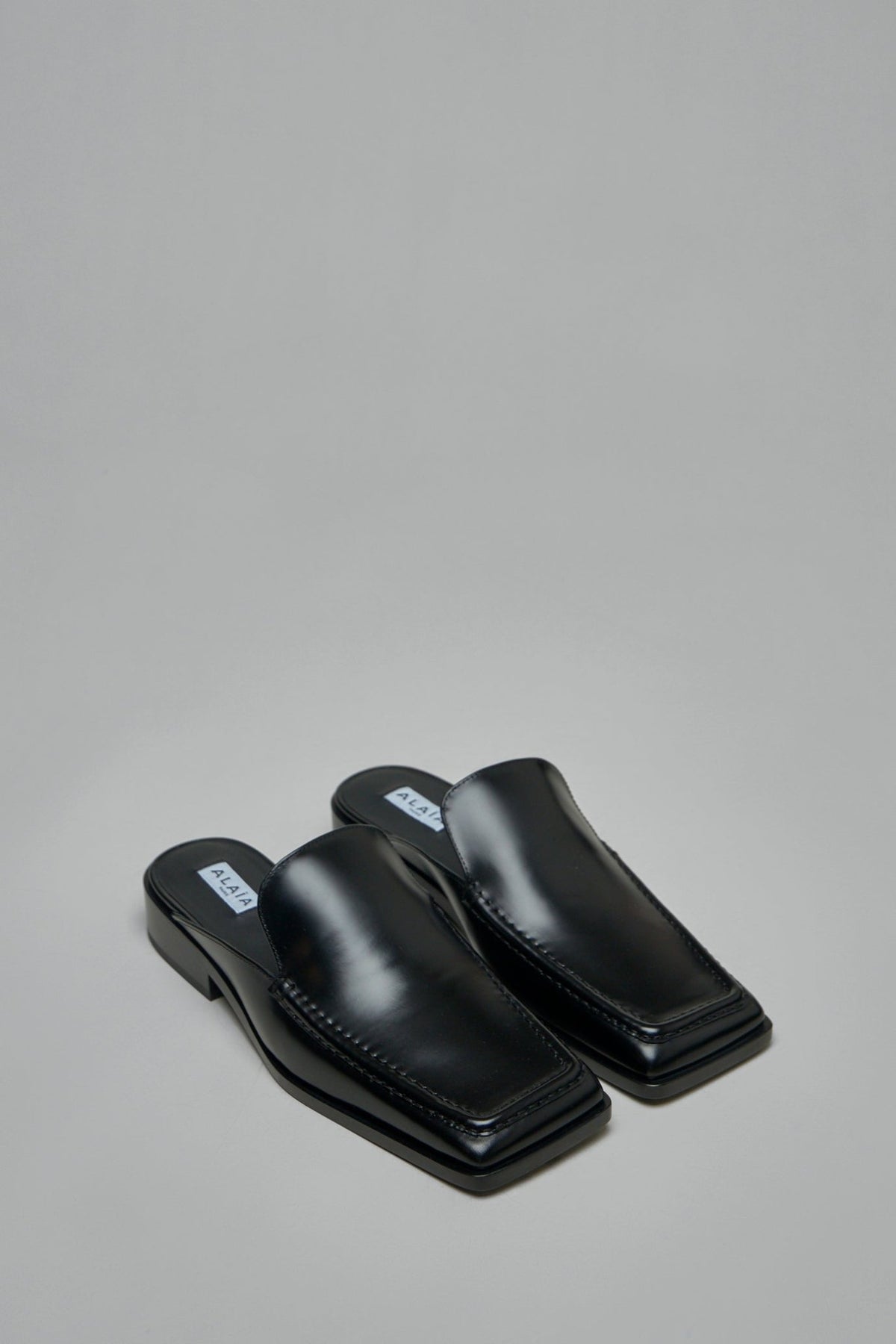Side view of Alaïa square loafer mules showing polished leather finish