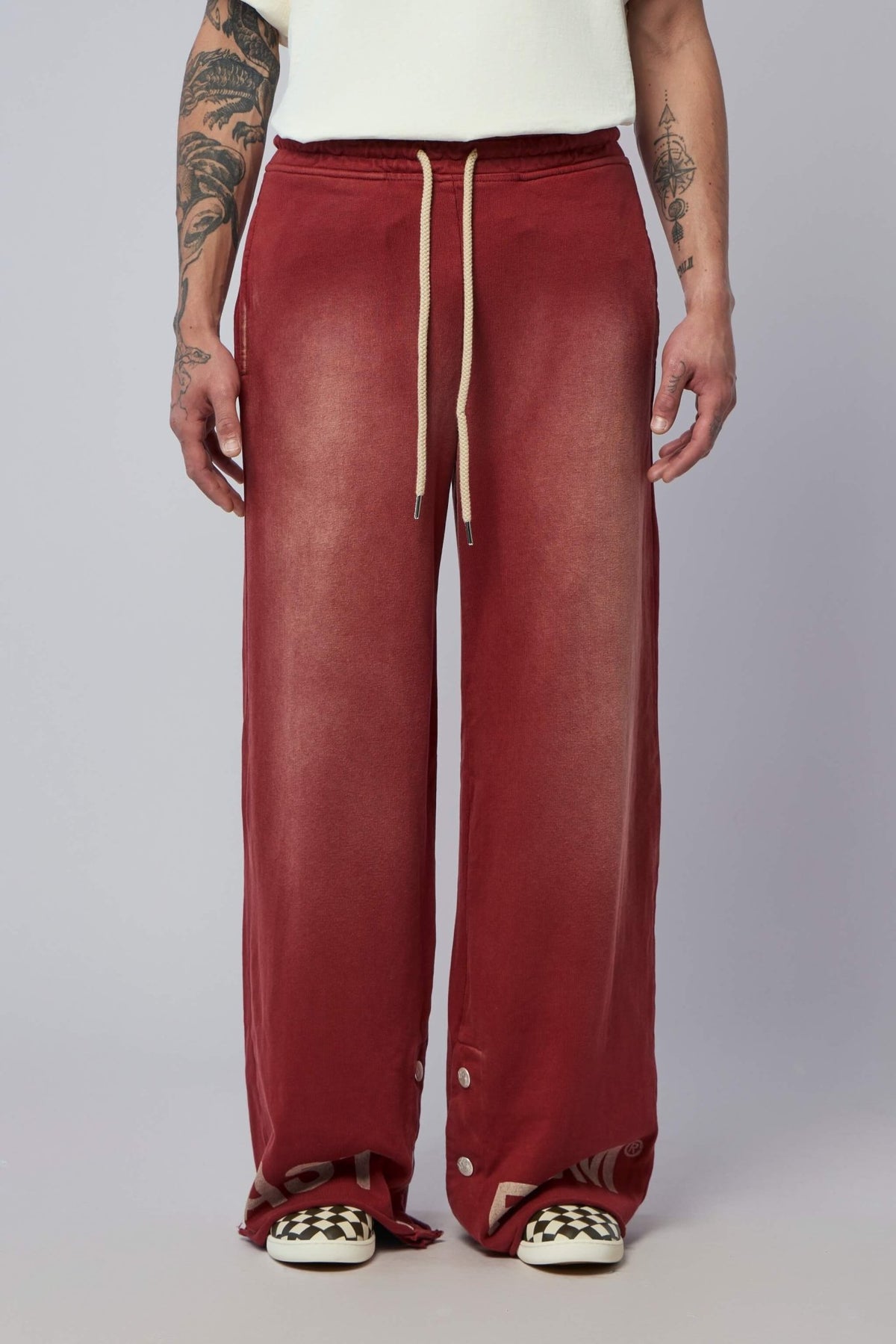 Close-up view of distinctive button details at hem of red cargo pants