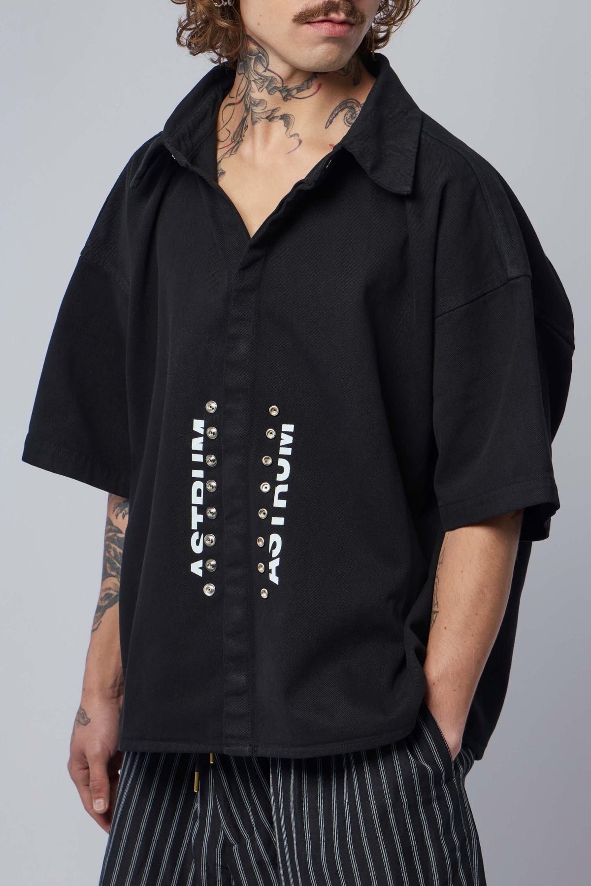 Model wearing relaxed fit Astrum Rivet Shirt with printed front branding