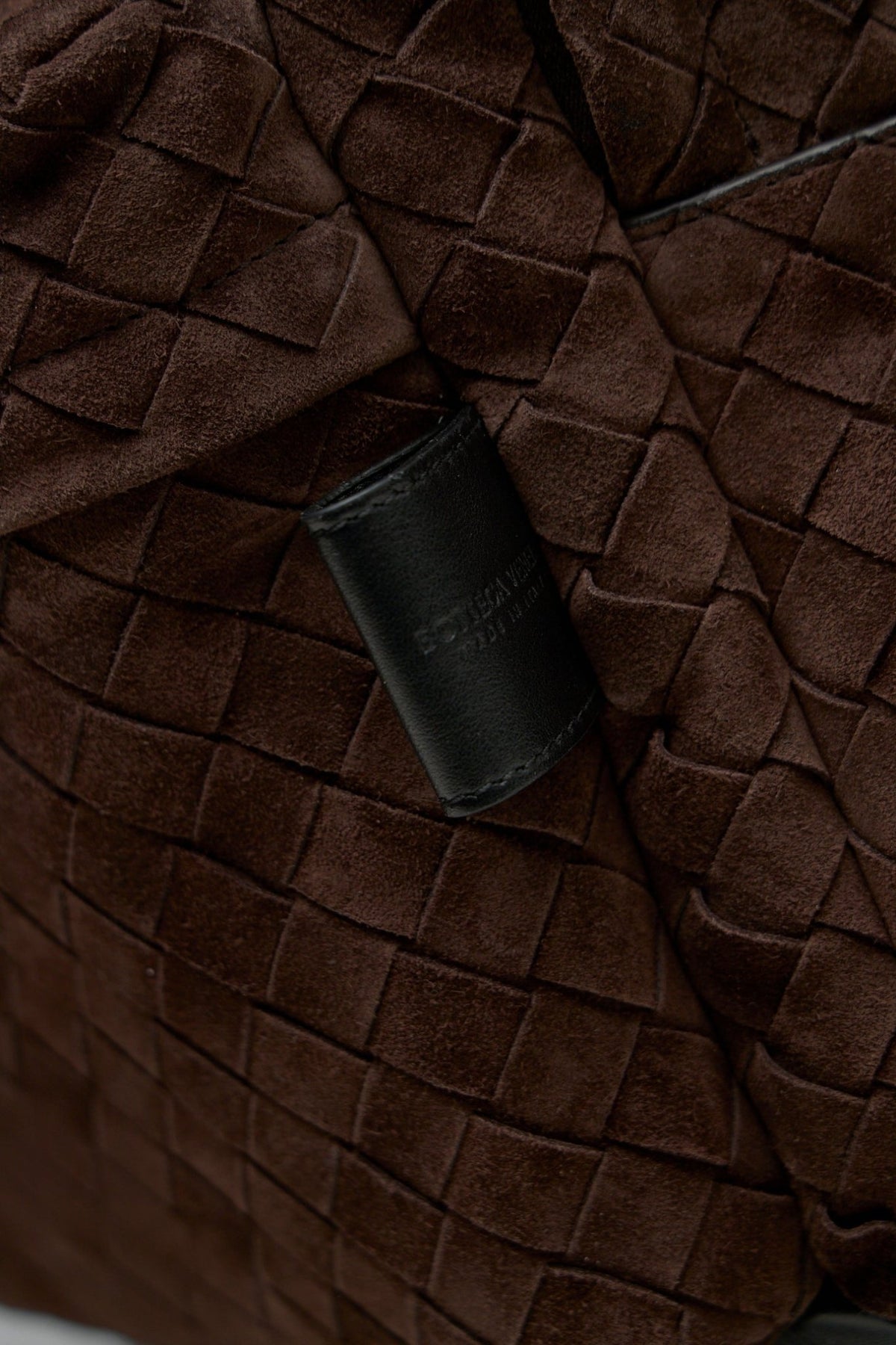 Side profile showing structured silhouette of brown leather luxury backpack