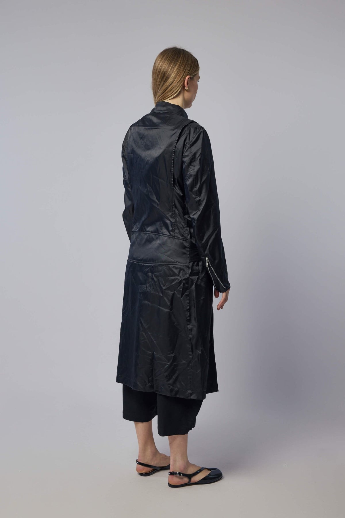 Detail shot of multiple front pockets and shiny finish on black coat