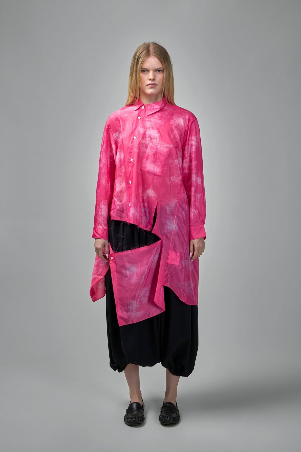 Close-up detail of asymmetrical snap-panel cutouts creating layered drape on pink blouse