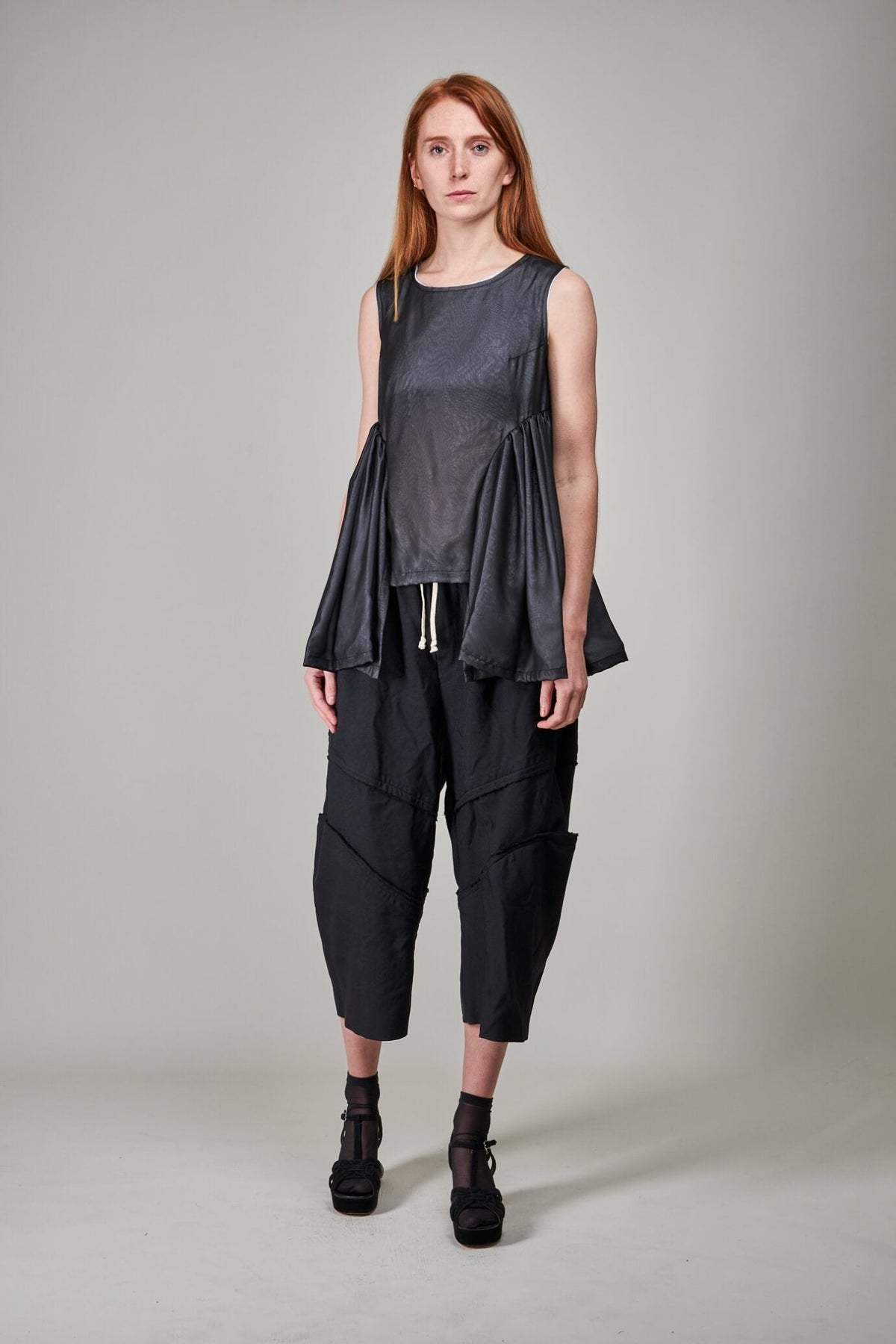 Close-up detail of unfinished edge detailing on black polyester blouse