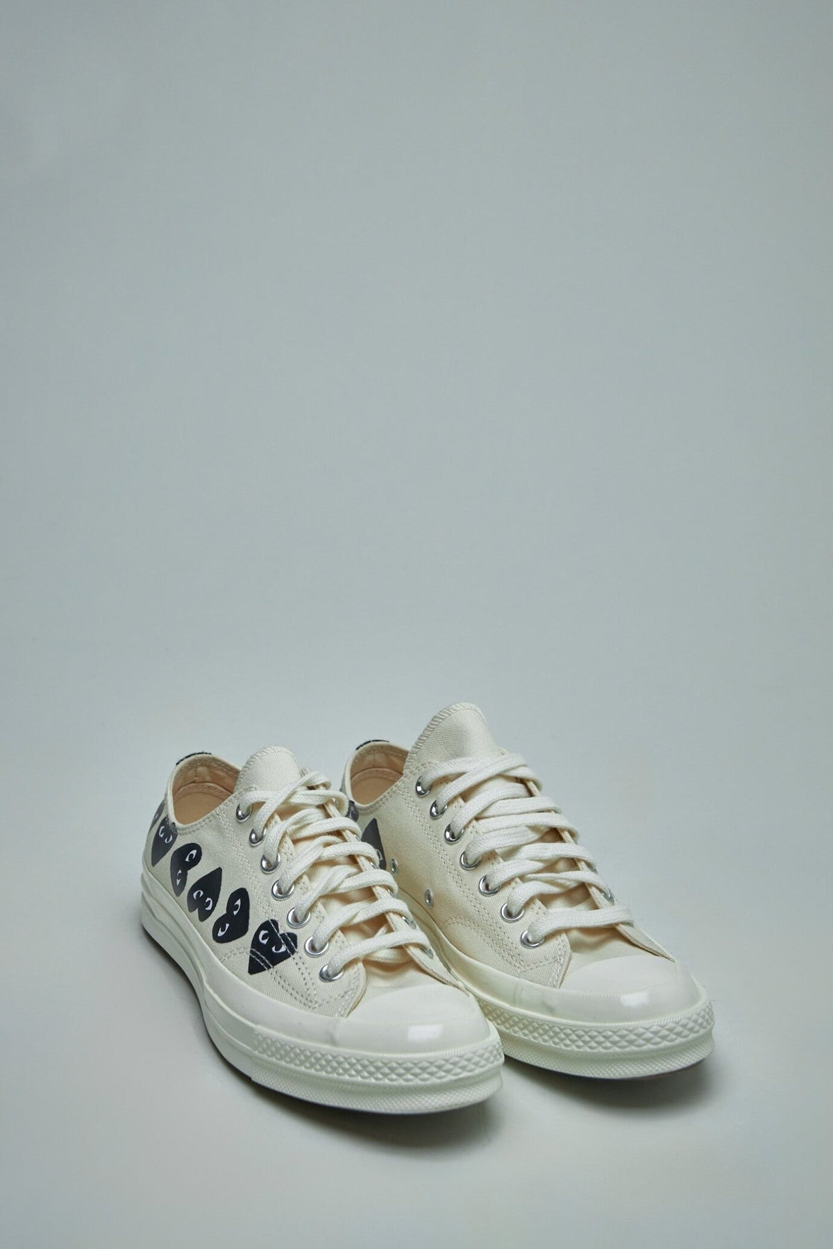Side view of white canvas sneakers featuring iconic red heart logos