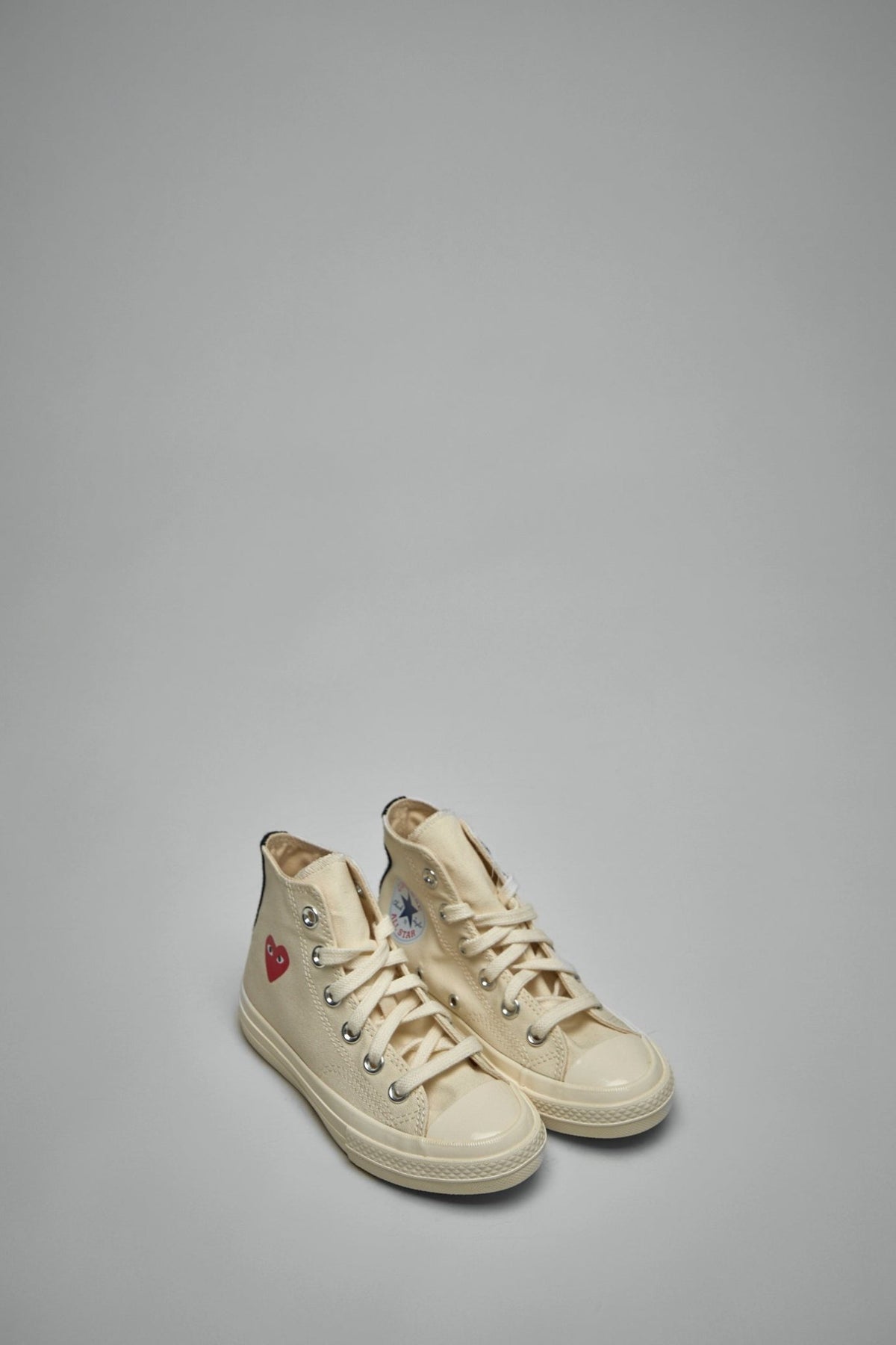 Side view of kids high top sneakers showing blue star patch and red heart branding