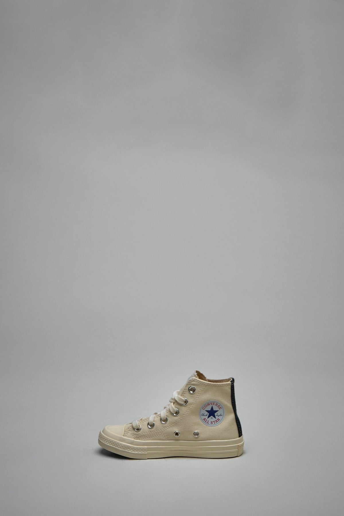 Back view of white canvas sneakers with black contrasting tab detail