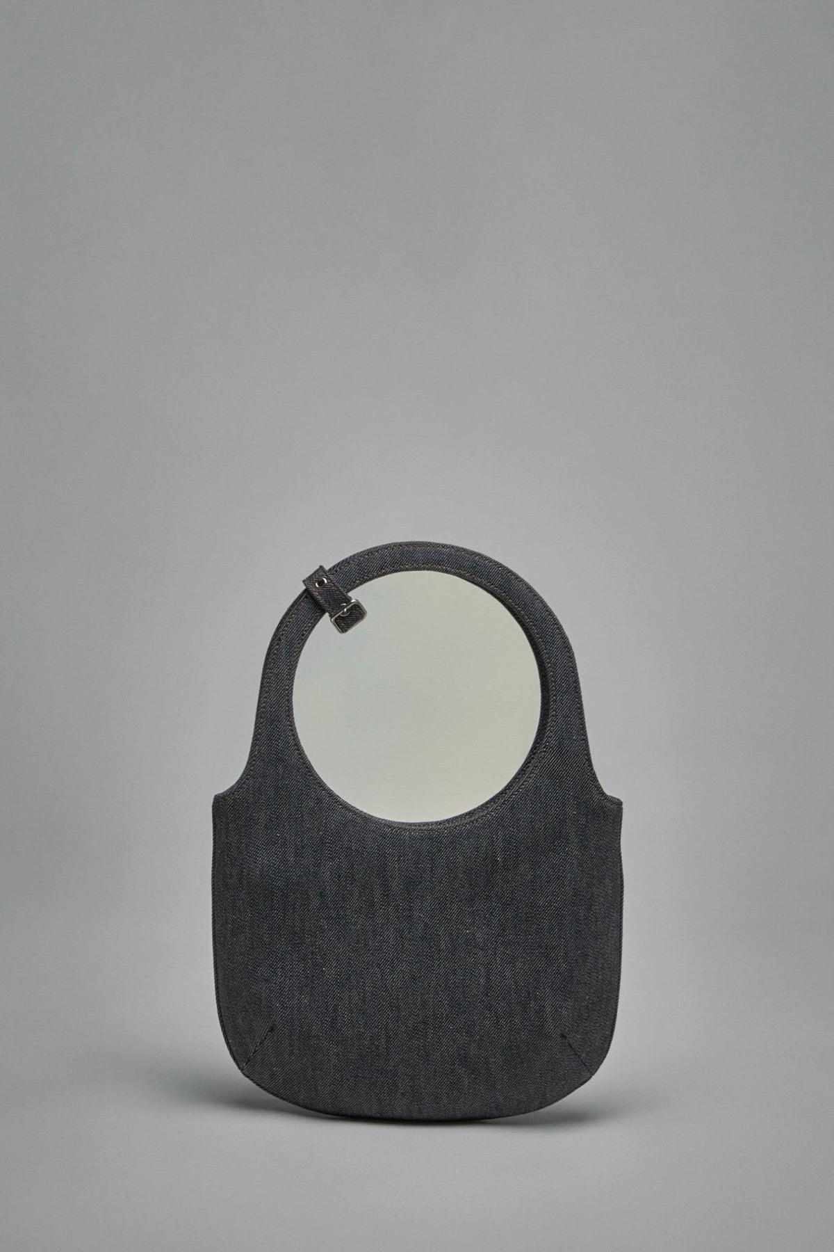 Side profile of Courrèges denim handbag displaying adjustable shoulder strap and top handles