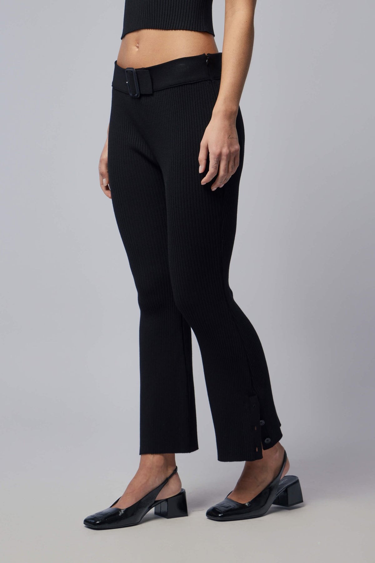 Side view showing flared silhouette of black Courrèges pants