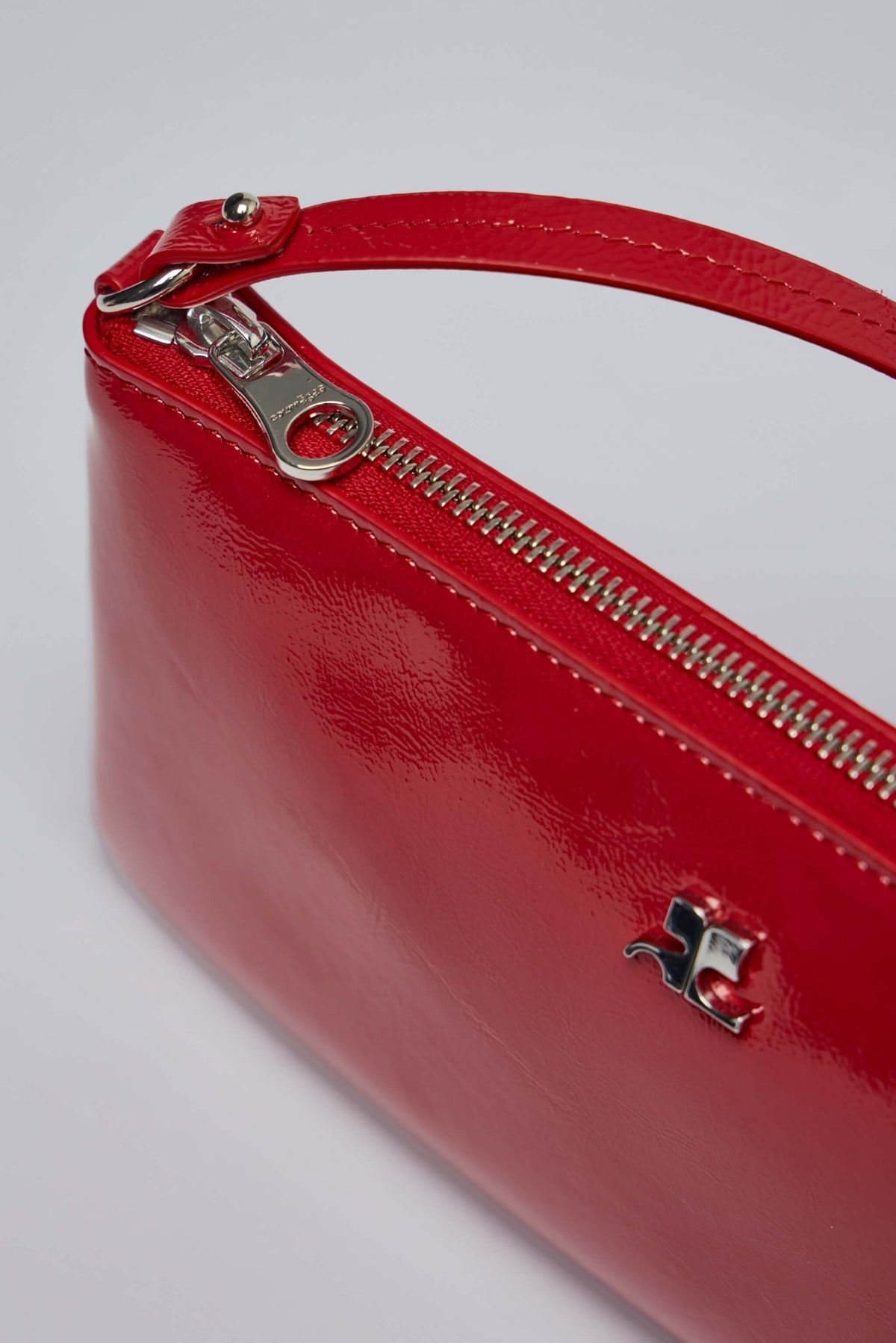 Detail shot of Courrèges minimalist silver logo on red patent leather