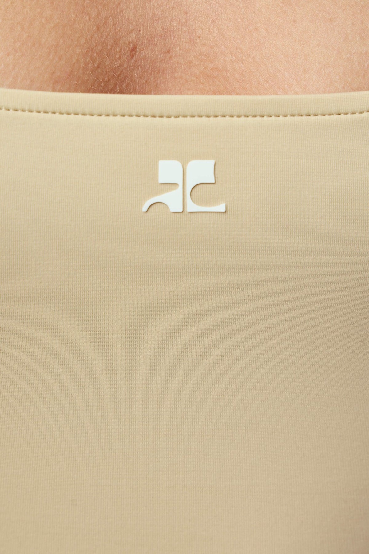 Flat lay of beige Courrèges one-piece showing smooth fabric texture