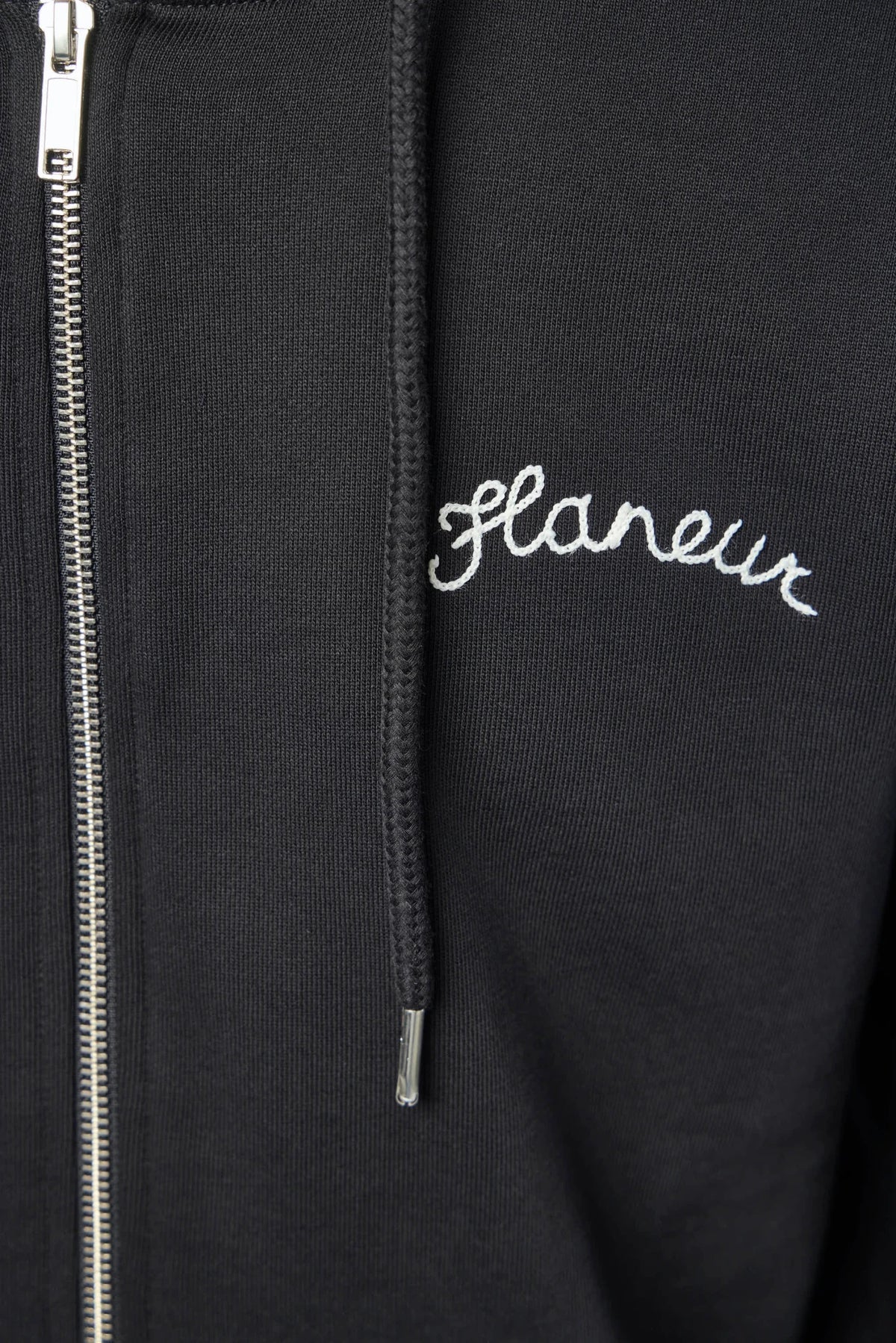 Detail shot of embroidered logo on FLÂNEUR Zip-Ups Signature Hoodie