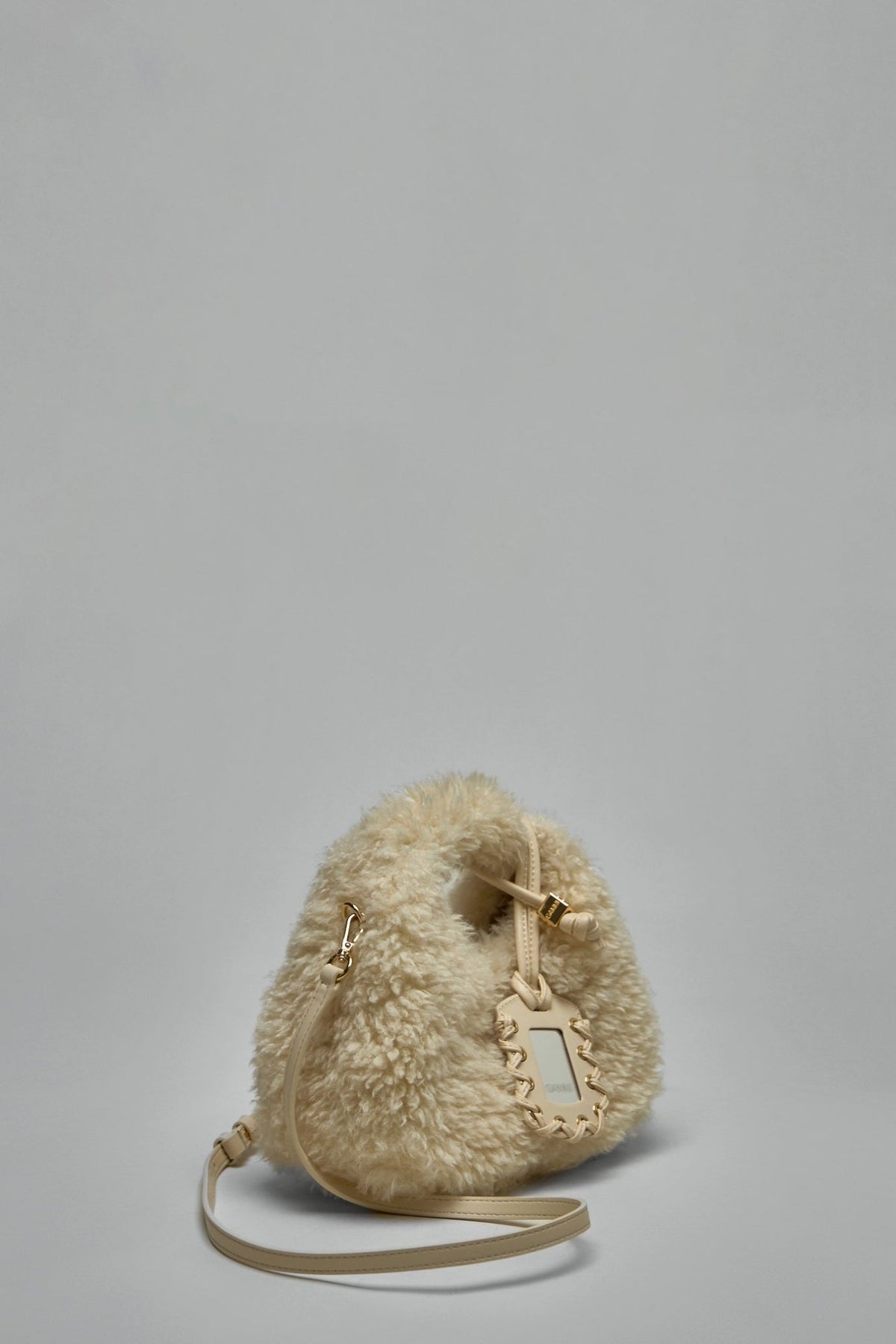 Close-up of circular cutout handle detail on cream shearling hobo bag