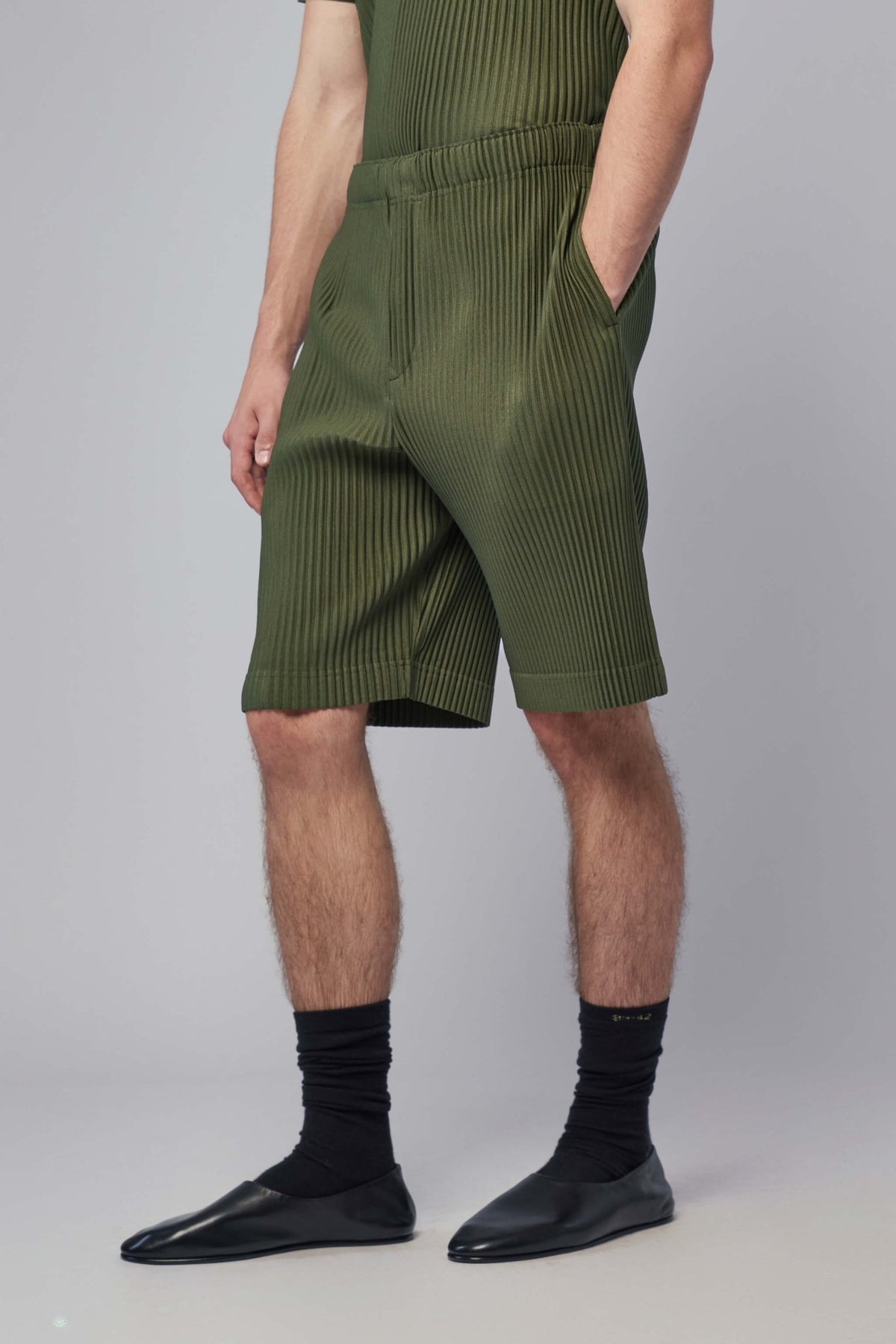Model wearing green Homme Plissé Issey Miyake knee-length shorts