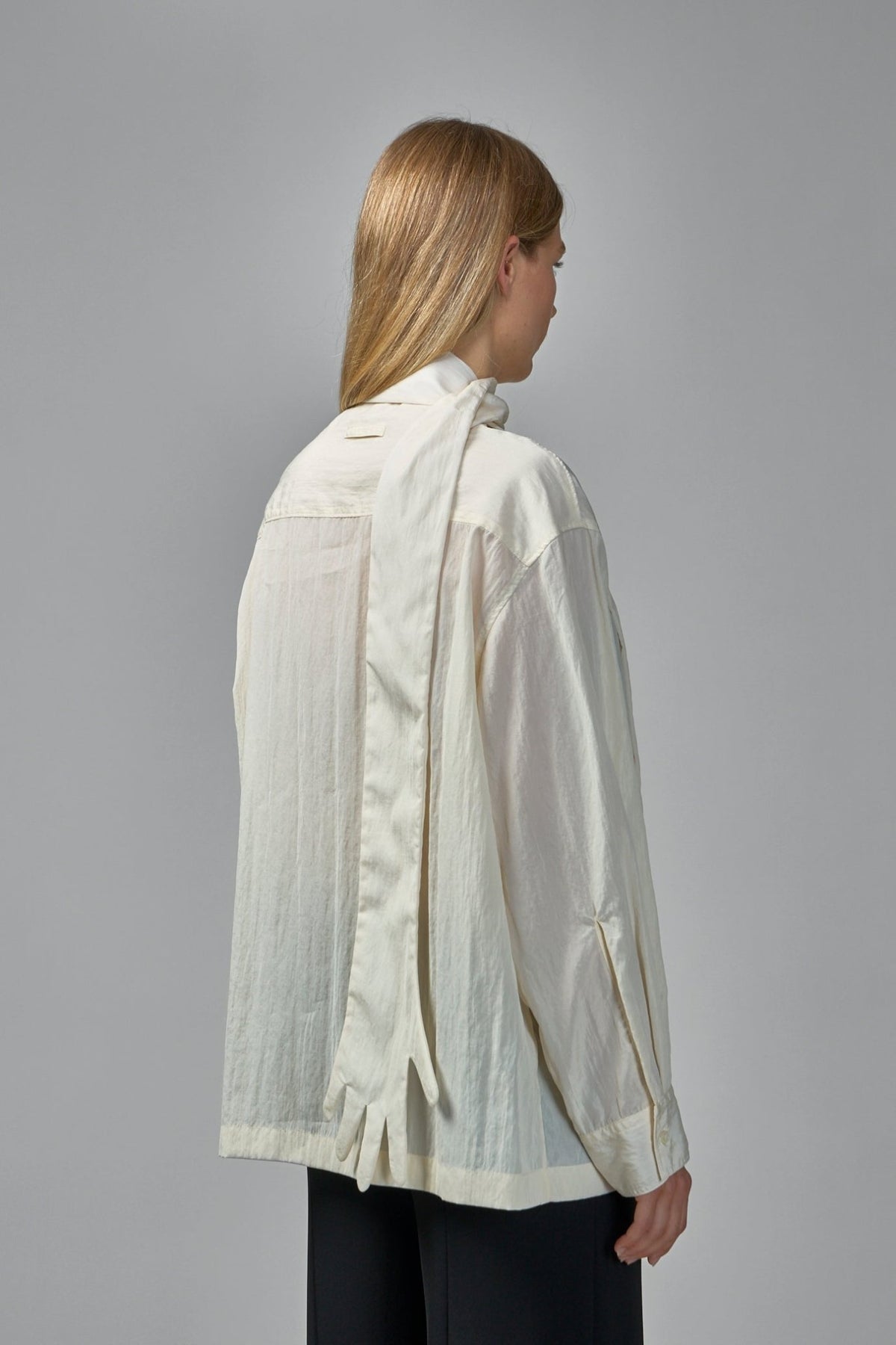 Model wearing Jean Paul Gaultier cream blouse with theatrical scarf-to-gloves design