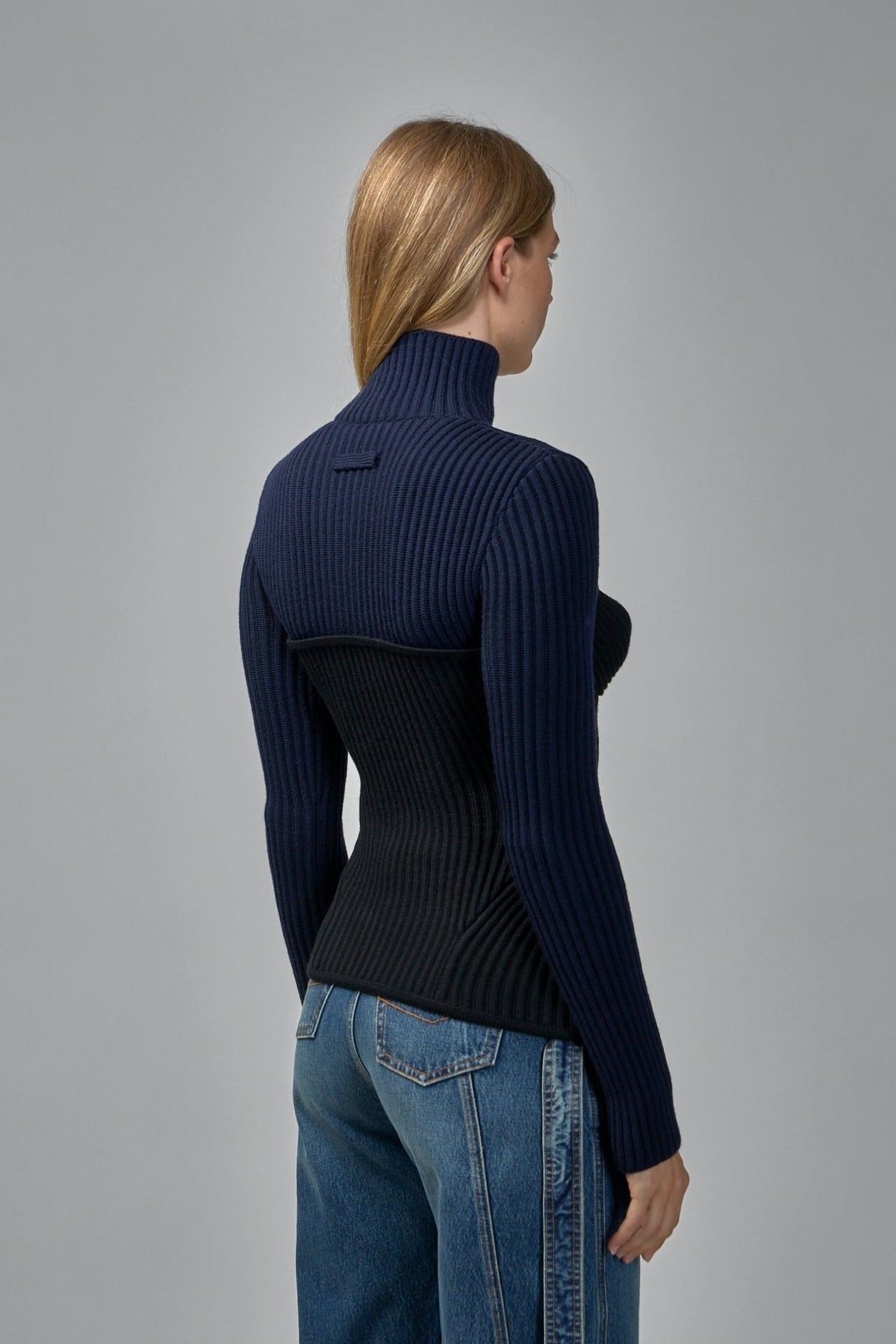 Side view showing fitted silhouette and sculptural cup detailing of designer turtleneck