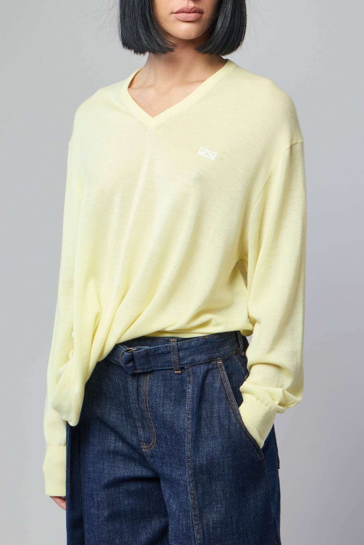 Model wearing Loewe draped sweater styled with tailored pants