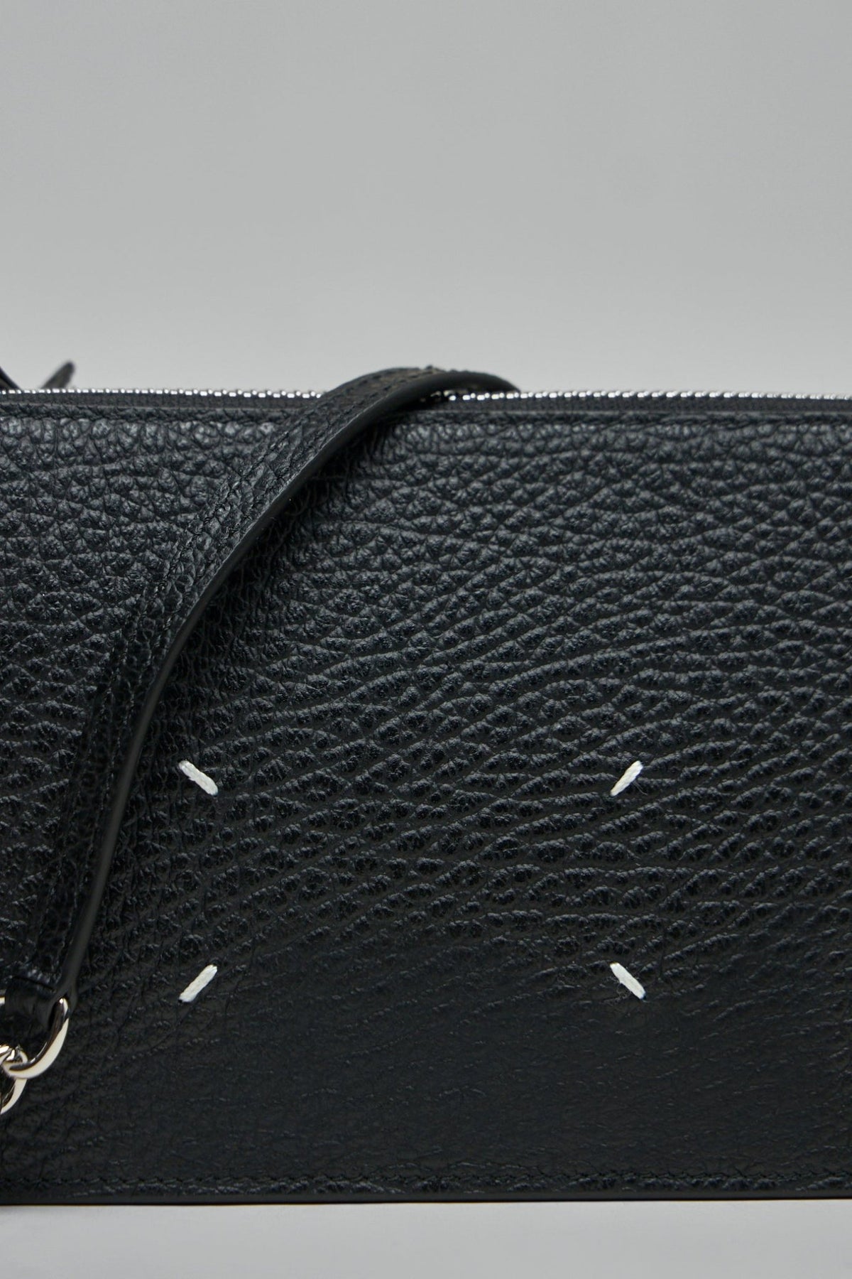 Side view of black leather crossbody bag with silver chain strap and leather pad