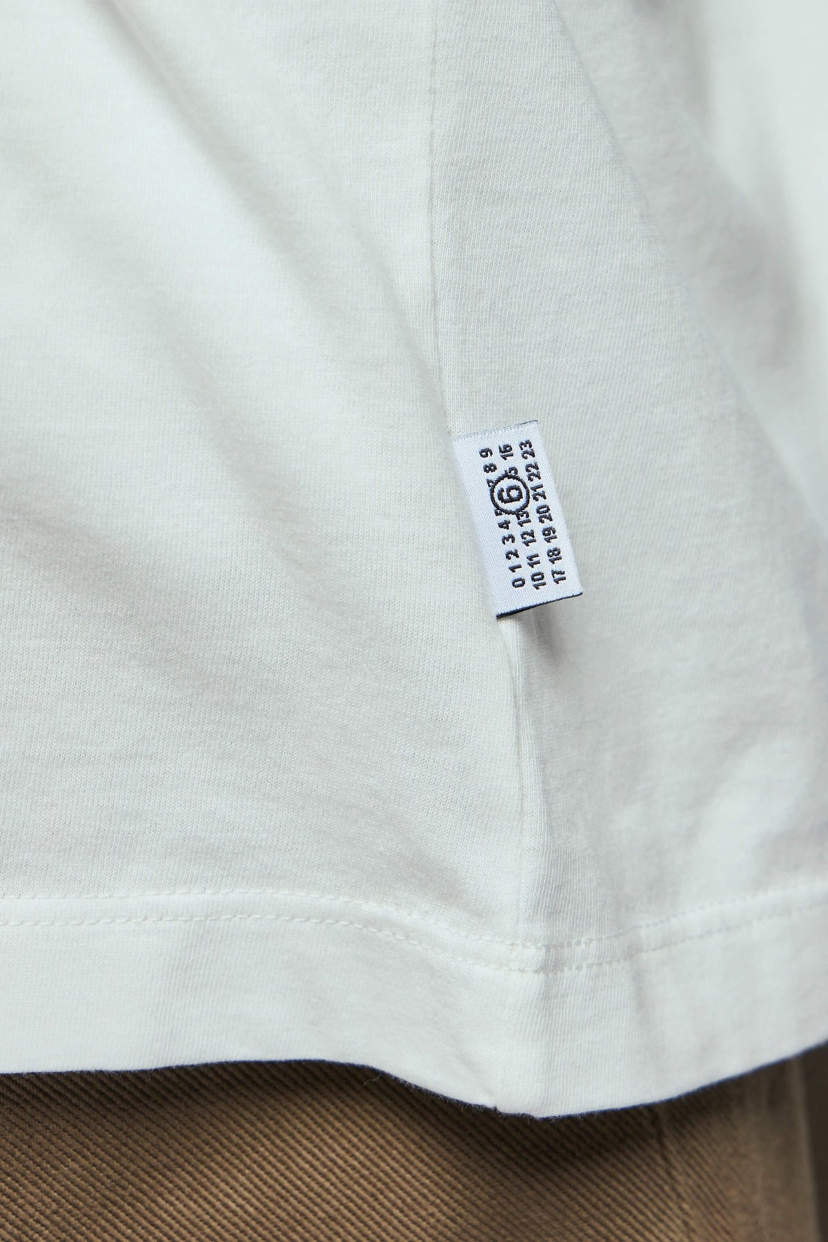 Side view showing MM6 Margiela brand tag on white cotton t-shirt