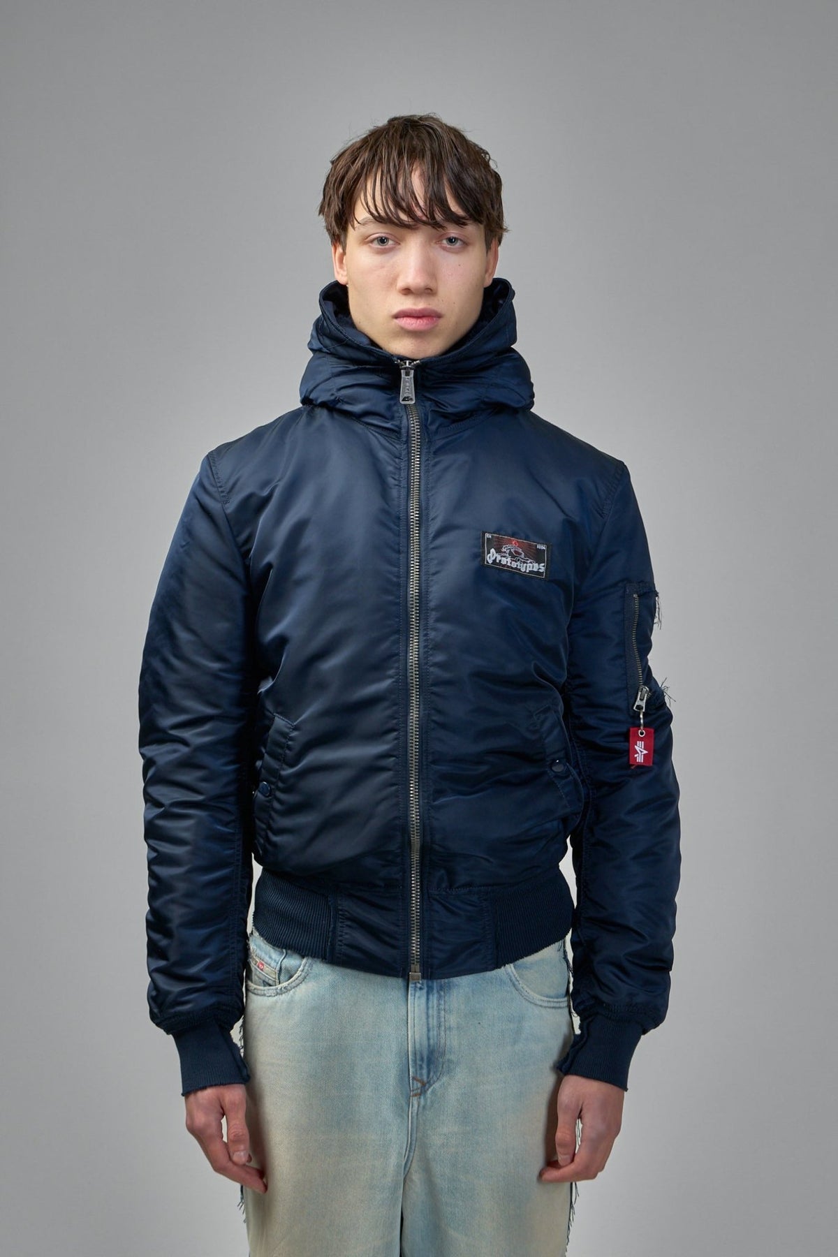 Close-up of bomber jacket zip closure and logo patch detail
