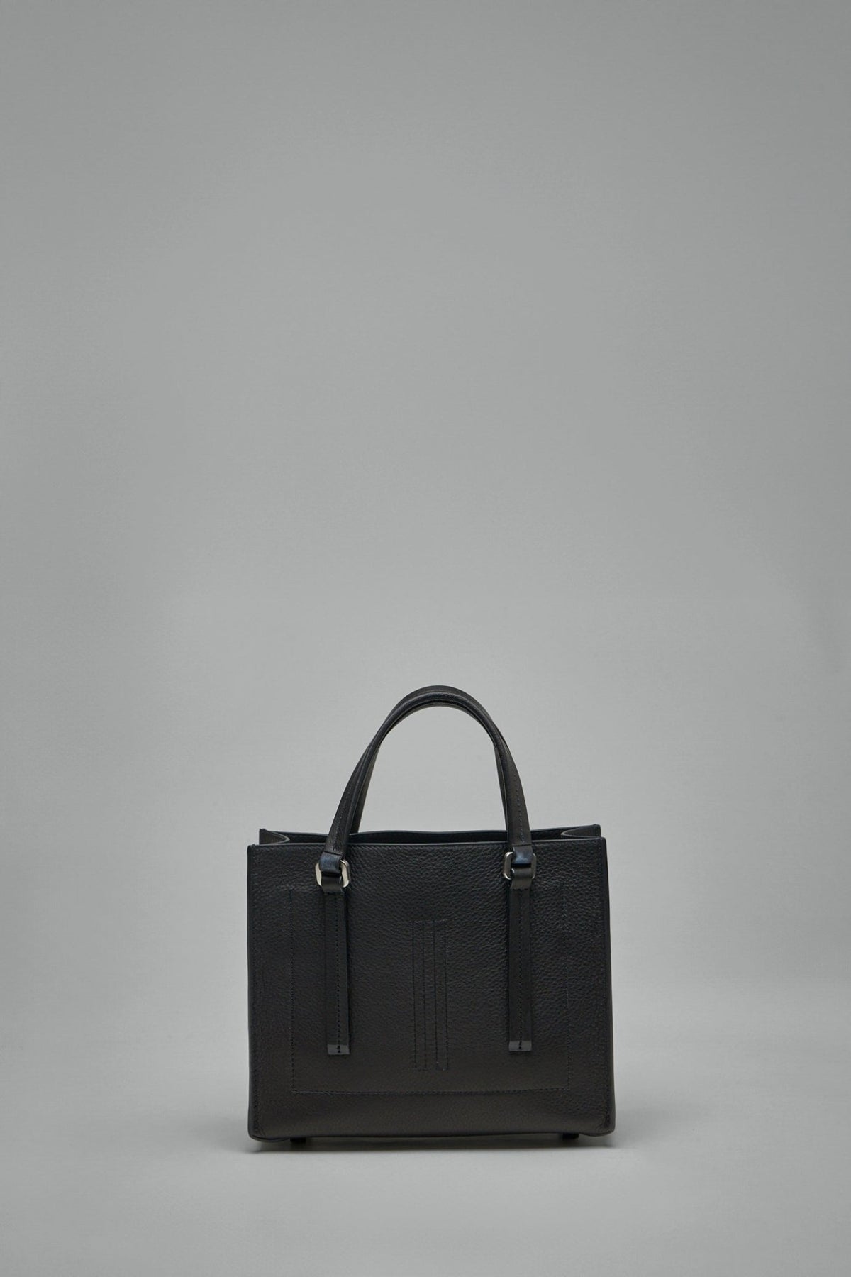 Side view of Mini Edith bag displaying architectural silhouette and leather feet
