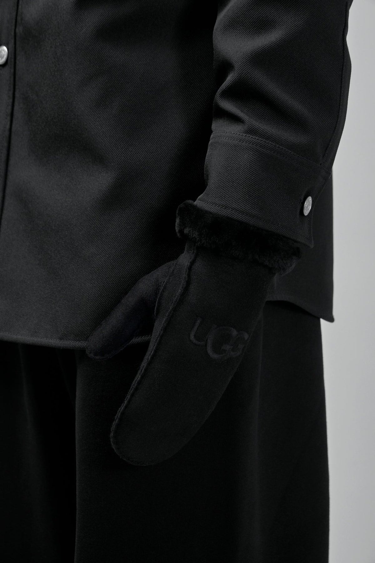 Pair of black UGG sheepskin mittens showing premium construction quality