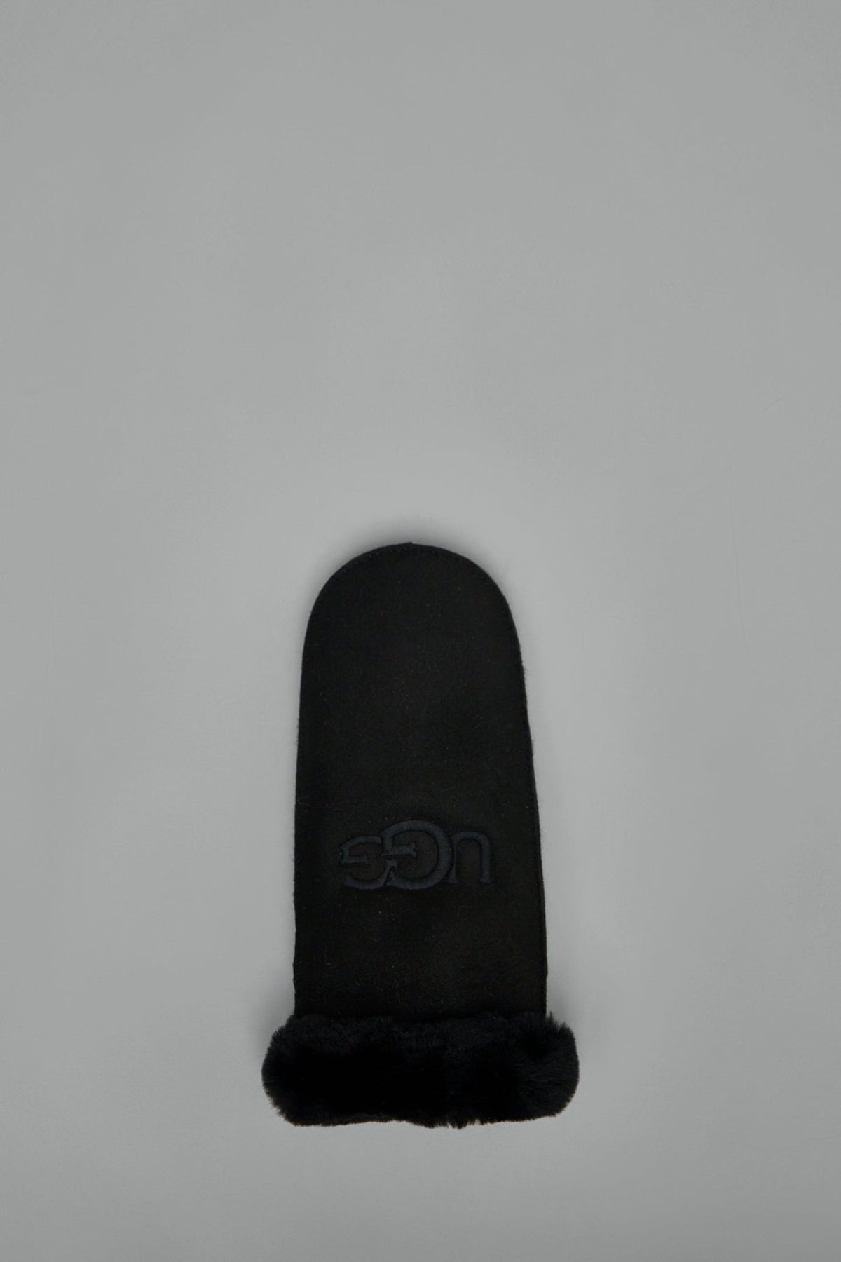 Close-up view of UGG sheepskin mitten showing plush texture and logo detail
