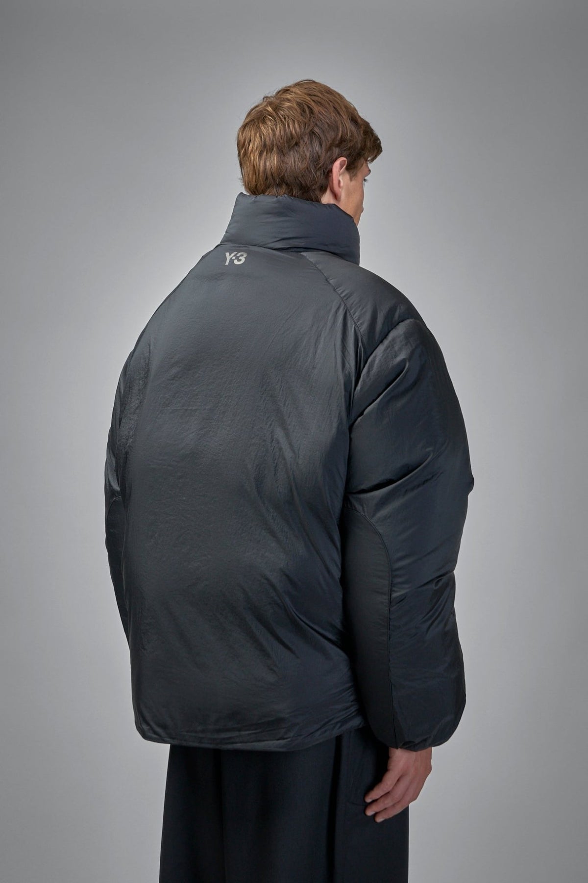 Back view of Y-3 down jacket displaying signature branding and horizontal seam details