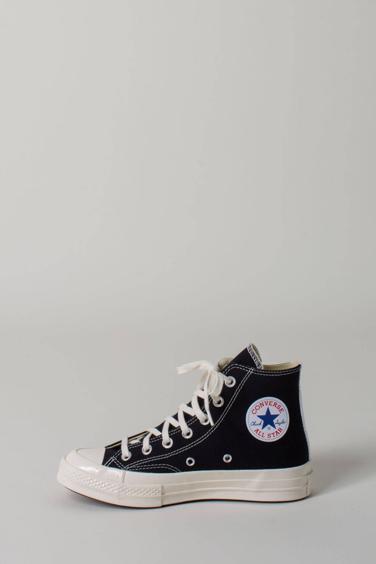 Detail shot of CDG PLAY heart logo on white canvas sneakers